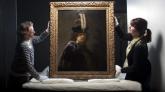 Conservators hold up a recently verified 1635 self-portrait by Dutch artist Rembrandt van Rijn