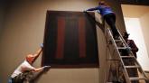 Tate Modern employees in London adjust Mark Rothko's Black on Maroon, which went back on display Tuesday, more than a year and a half after it was defaced with black ink by a vandal